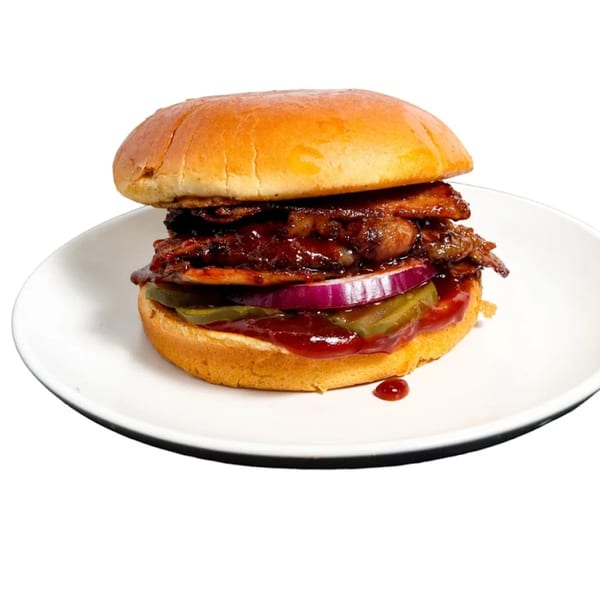 A Country Smokin Burgers' BBQ burger with pulled pork, red onion, and pickles on a white plate.